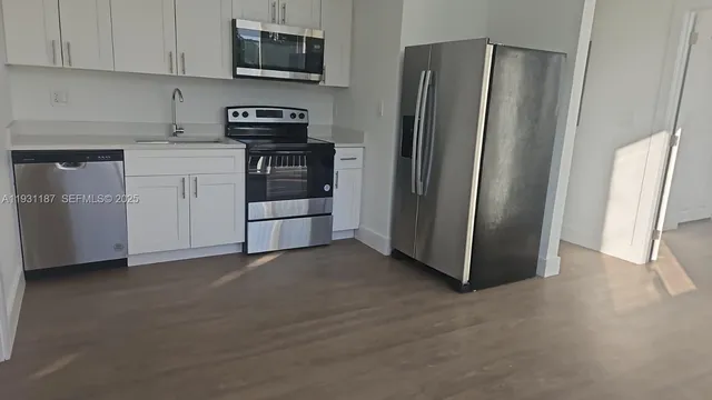 a kitchen with stainless steel appliances granite countertop a refrigerator a stove and a sink