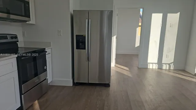 a view of a kitchen with a stove wooden cabinets and a refrigerator