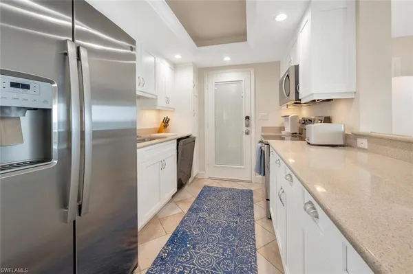 a kitchen with stainless steel appliances granite countertop a refrigerator a sink and white cabinets