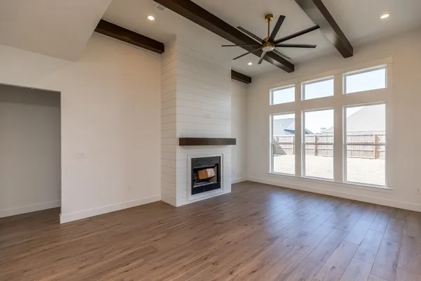 a view of a livingroom with a fireplace a ceiling fan and wooden floor
