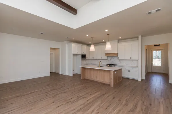 a large kitchen with a center island wooden floor stainless steel appliances and a window
