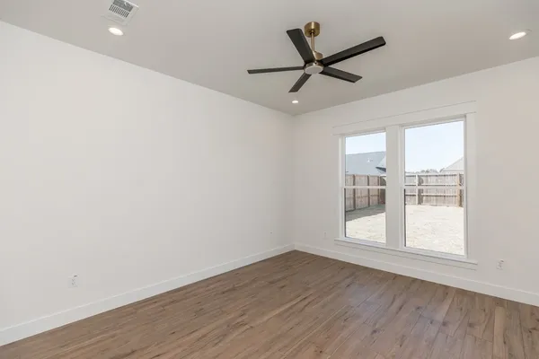 a view of a big room with wooden floor and windows