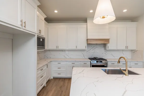 a kitchen with granite countertop a sink a stove and cabinets