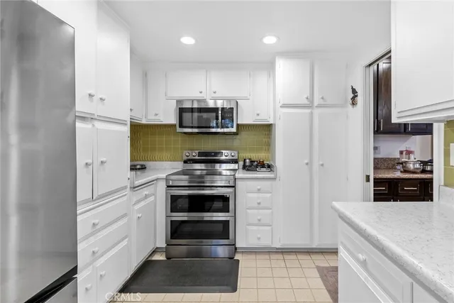a kitchen with stainless steel appliances a refrigerator stove and white cabinets
