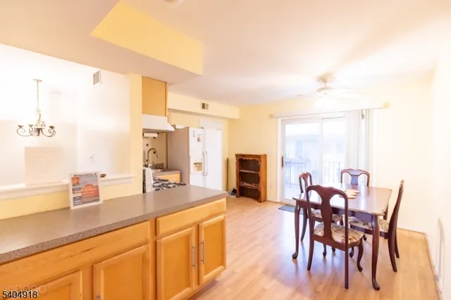 a dining hall with stainless steel appliances kitchen island granite countertop a table chairs and a refrigerator