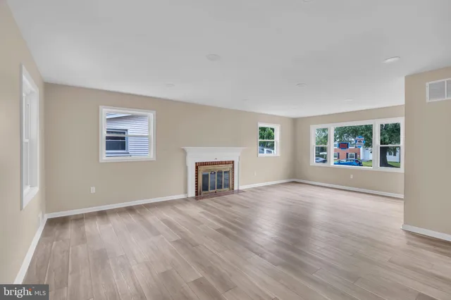 an empty room with windows and fireplace