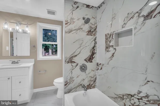 a bathroom with a granite countertop sink a toilet and shower
