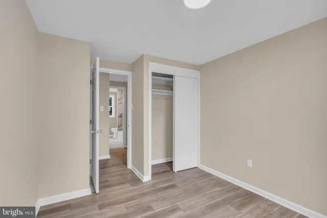 a view of an empty room with wooden floor and closet