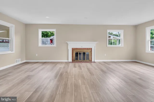 wooden floor fireplace and windows in an empty room
