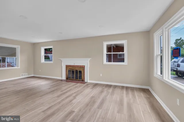 a view of empty room with wooden floor and fireplace
