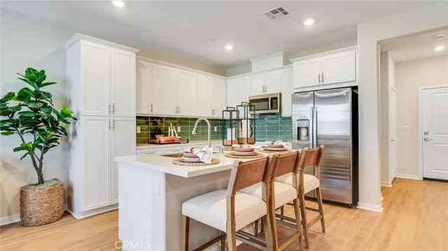 a kitchen with stainless steel appliances a dining table chairs refrigerator and sink