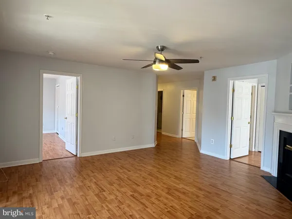a view of an empty room with wooden floor and a ceiling fan