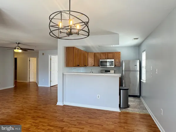 an empty room with kitchen view and wooden floor