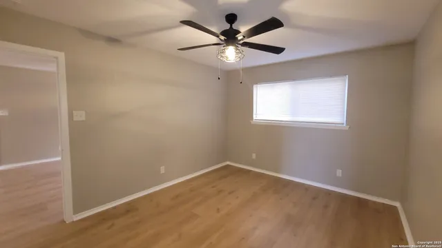 an empty room with a window and a fan