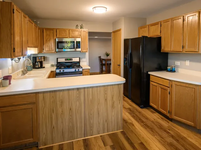 a kitchen with stainless steel appliances a refrigerator a sink a stove a microwave and wooden cabinets