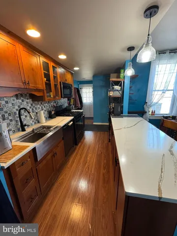 a kitchen with stainless steel appliances granite countertop a sink a stove and a wooden floors