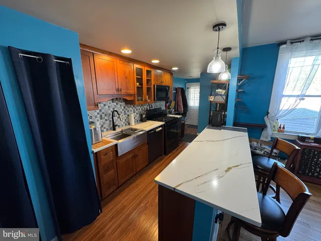 a kitchen with stainless steel appliances granite countertop a refrigerator a sink dishwasher a stove and white countertops with wooden floor