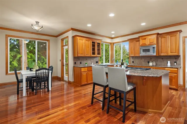 a kitchen with stainless steel appliances granite countertop a stove a kitchen island a table and chairs