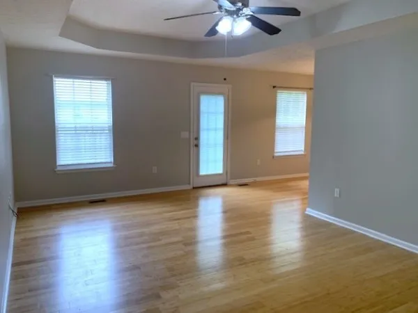a view of an empty room with wooden floor and a window