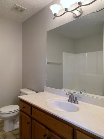 a bathroom with a granite countertop sink a toilet and a mirror