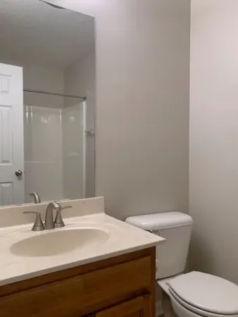a bathroom with a sink a toilet a mirror and shower