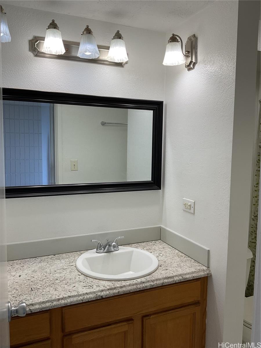 85-003 Pokai Bay Street, Unit 403 Waianae, HI 96792 - Photo 17 of 22 a bathroom with a granite countertop sink and a mirror