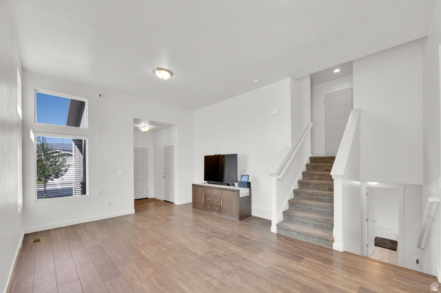 6120 North Sheps Ridge Road Eagle Mountain, UT 84005 - Photo 4 of 43 Spacious living area featuring wood-finish flooring, high ceilings, multiple windows, and a carpeted staircase with a white banister