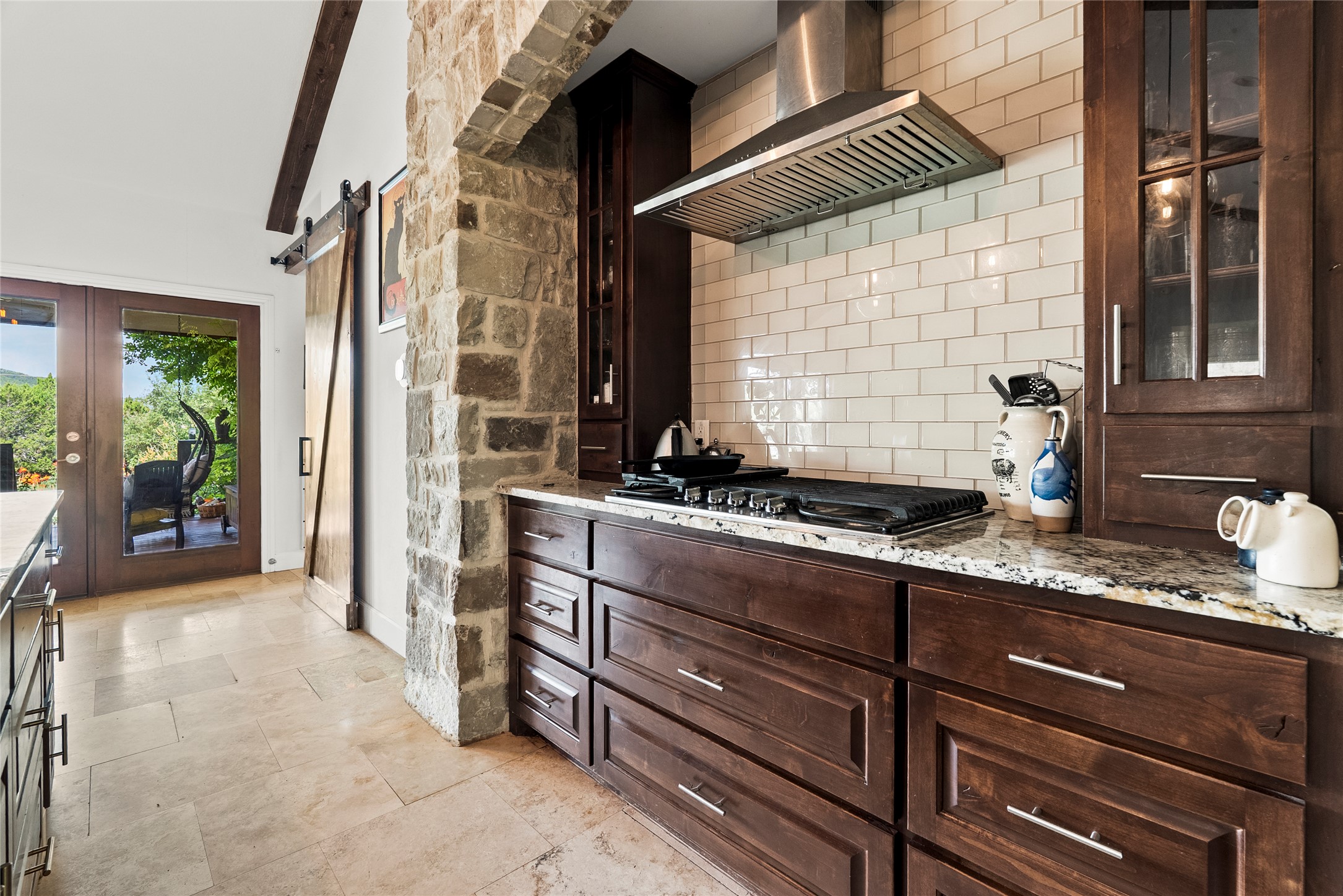 23224 Nameless Road Leander, TX 78641 - Photo 10 of 23 A well-appointed kitchen showcasing rich wood cabinetry, granite countertops, and a modern gas range set against a subway tile backsplash.