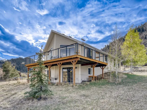 a view of a big house that has a small yard and large trees