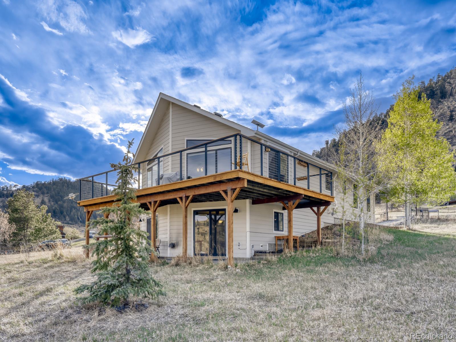 32020 Robinson Hill Road Golden, CO 80403 - Photo 2 of 28 a view of a big house that has a small yard and large trees