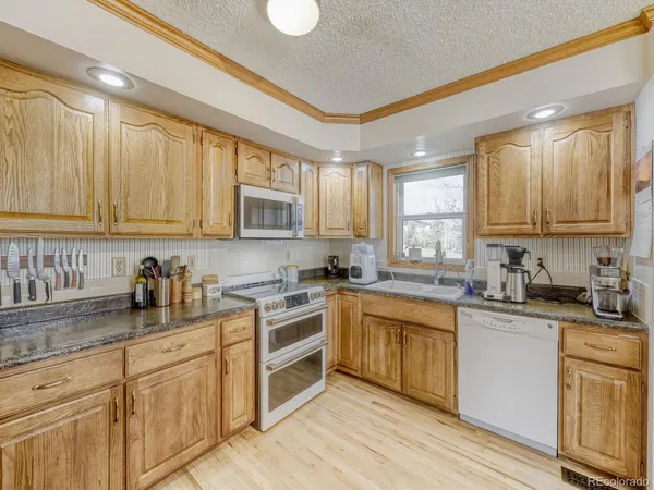 a kitchen with granite countertop white cabinets sink and stainless steel appliances