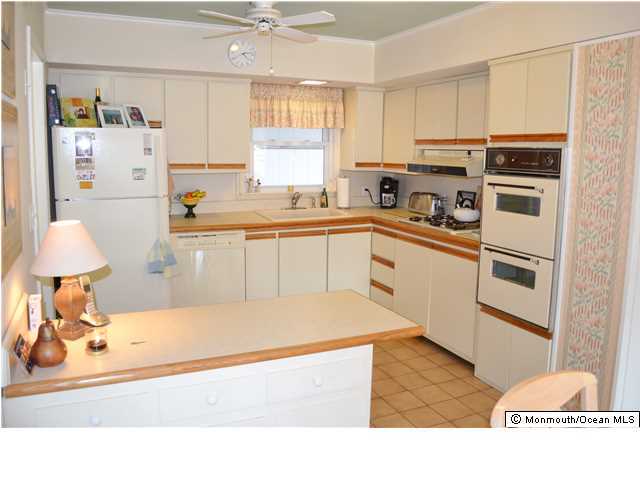 1417 Rue Mirador Point Pleasant, NJ 08742 - Photo 6 of 21 a kitchen with stainless steel appliances granite countertop a refrigerator sink stove and white cabinets