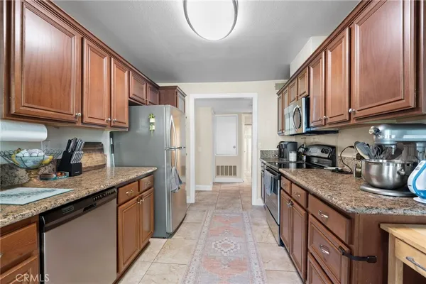 a kitchen with stainless steel appliances granite countertop a sink stove refrigerator and cabinets