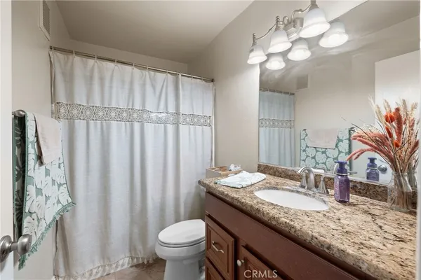 a bathroom with a granite countertop sink a toilet and a mirror