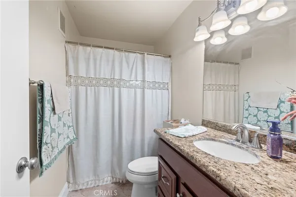 a bathroom with a granite countertop sink a toilet and a mirror