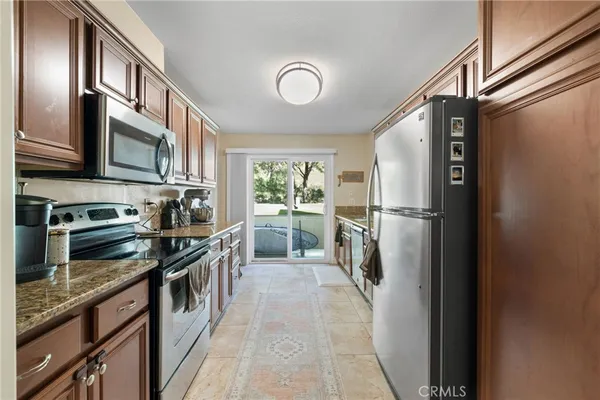 a kitchen with stainless steel appliances granite countertop a refrigerator a stove and a sink