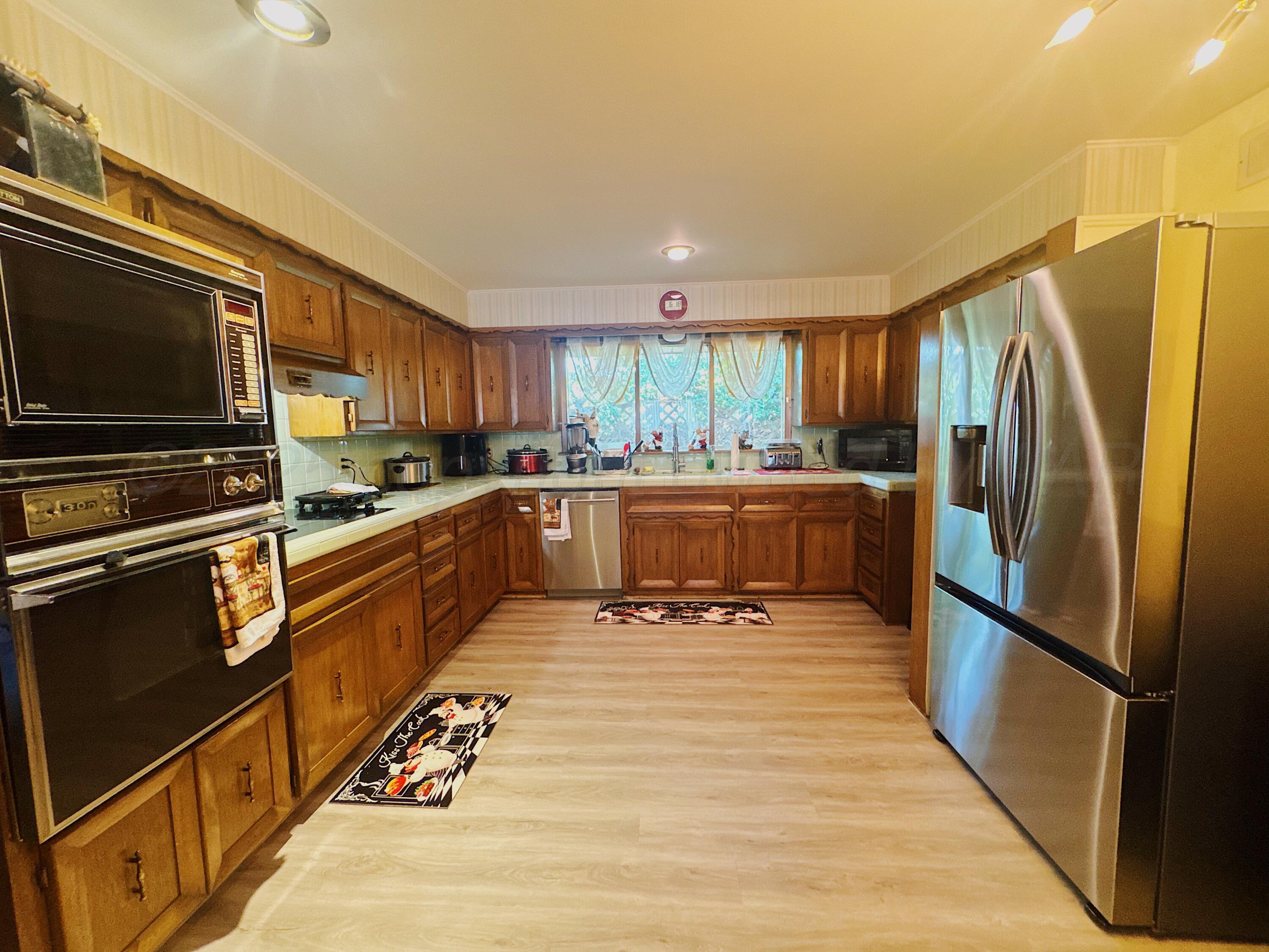 1421 South Fordham Street Perryton, TX 79070 - Photo 6 of 20 a kitchen with stainless steel appliances granite countertop a refrigerator stove microwave and sink