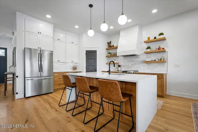 a kitchen with stainless steel appliances granite countertop a sink a stove and wooden floor