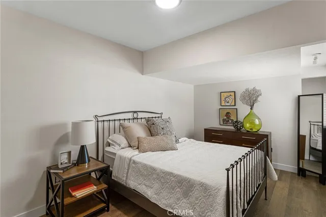 a bedroom with a bed and a dresser with wooden floor