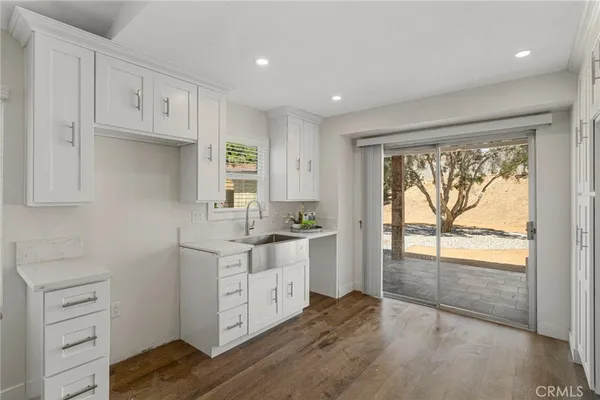 a kitchen with white cabinets and wooden floors