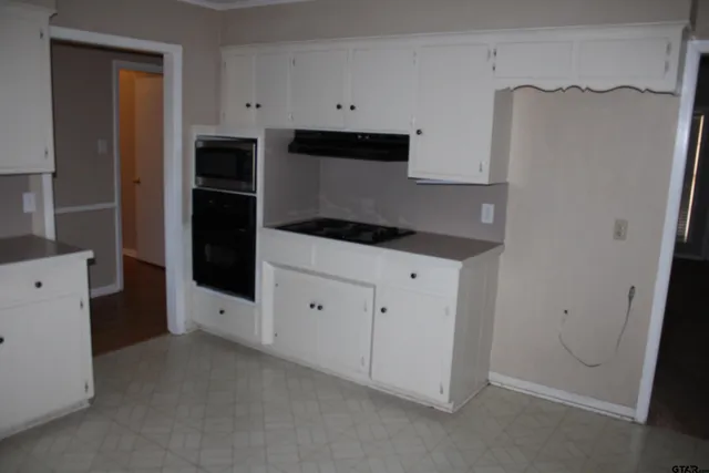 a kitchen with white cabinets and refrigerator