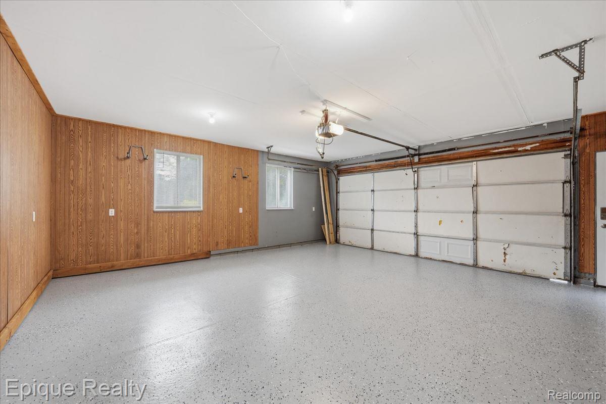 1221 Rhodes Road Lake Orion, MI 48360 - Photo 42 of 72 Two-car garage featuring a light gray speckled epoxy floor, wood-paneled walls, two windows, and an overhead garage door opener