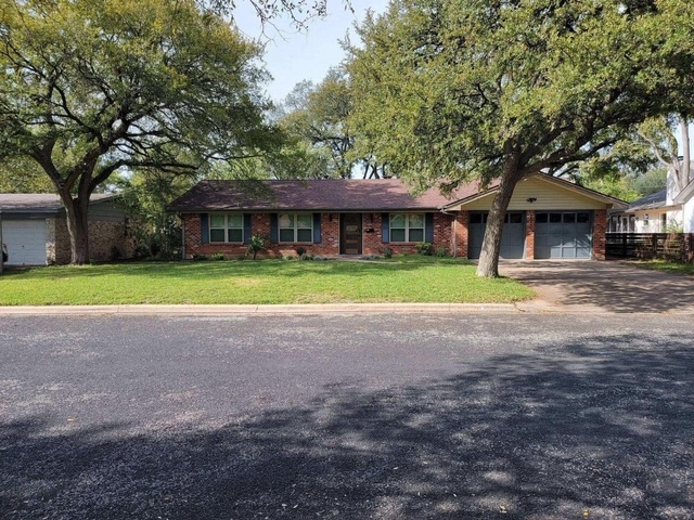 a front view of a house with a yard and trees