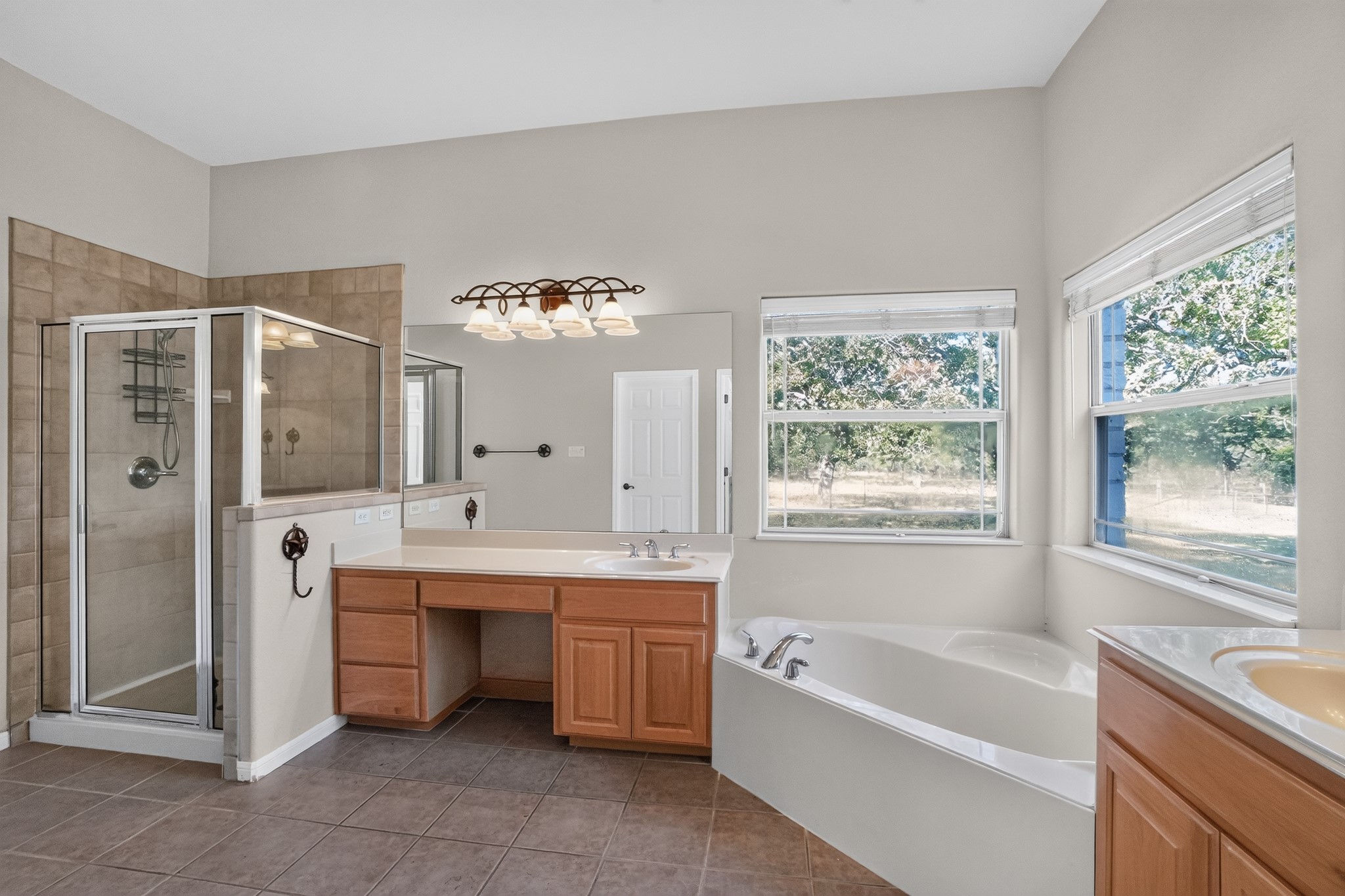 986 High Grove Road Cedar Creek, TX 78612 - Photo 24 of 30 A spacious bathroom features a corner soaking tub and glass-enclosed shower alongside tile flooring.