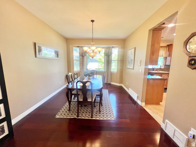 369 Culross Circle Tooele, UT 84074 - Photo 6 of 54 Dining area featuring rich wood-finish flooring, a bay window with natural light, and a prominent overhead chandelier