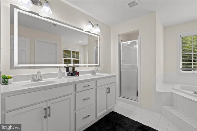 a bathroom with a double vanity sink a mirror and a bathtub