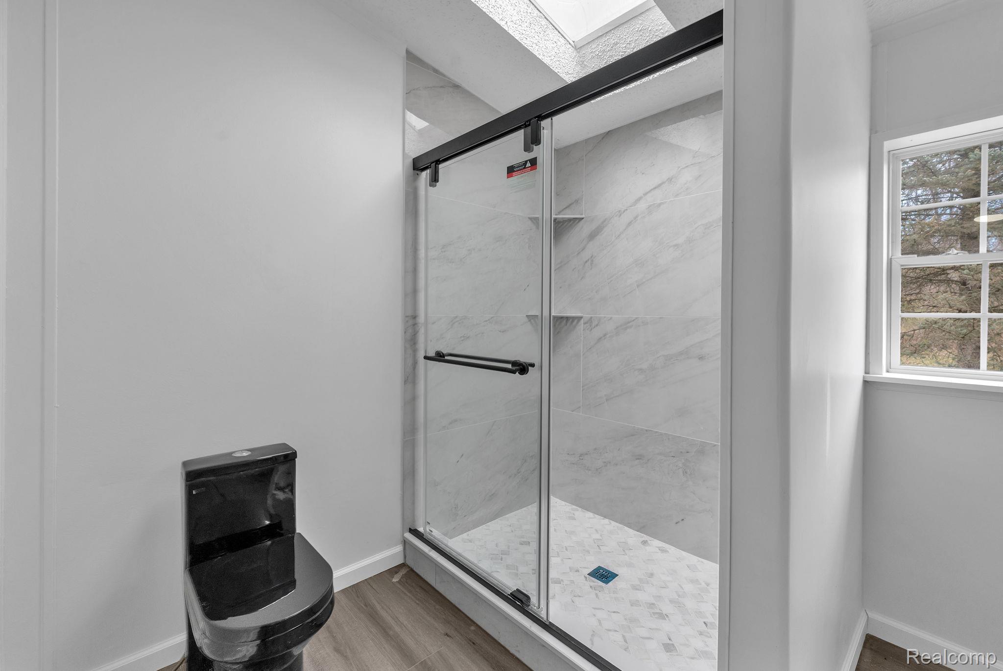 36085 Wick Road Romulus, MI 48174 - Photo 31 of 43 Full bathroom with a marble finish shower, a skylight, and light wood-style flooring