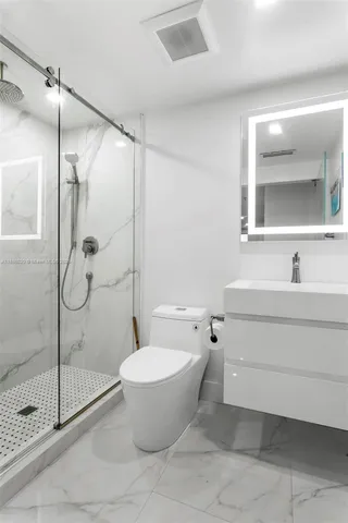 a bathroom with a granite countertop sink toilet and shower