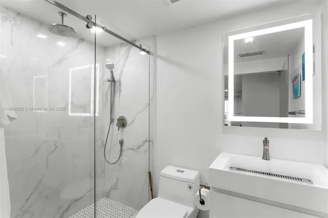 a bathroom with a shower sink vanity mirror and toilet