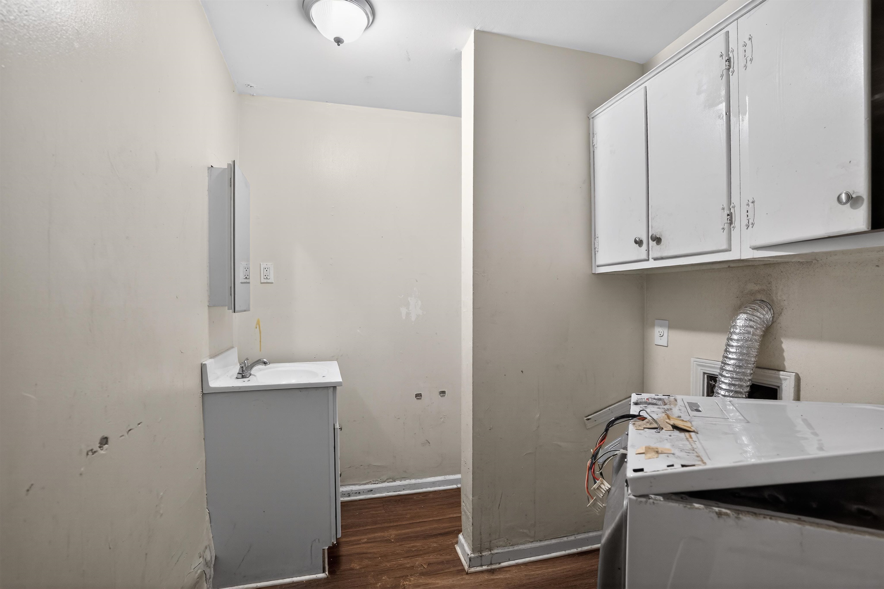 1890 Pennel Road Memphis, TN 38116 - Photo 25 of 25 Laundry area with wood-finish flooring, overhead cabinetry, and wall-mounted light fixture